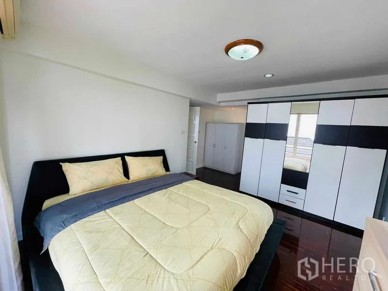 Detached House for rent in Watthana, Bangkok - Primary bedroom with king bed, built-in wardrobe, and polished wood floors.