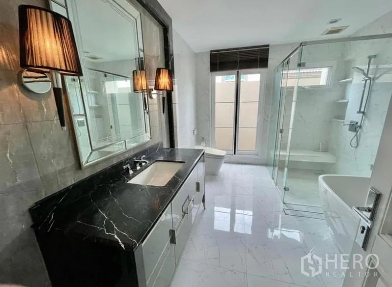 独立式住宅 出租在Bang Phli, Samut Prakan - 优雅浴室，黑色石材台面、玻璃淋浴间和浸泡浴缸。