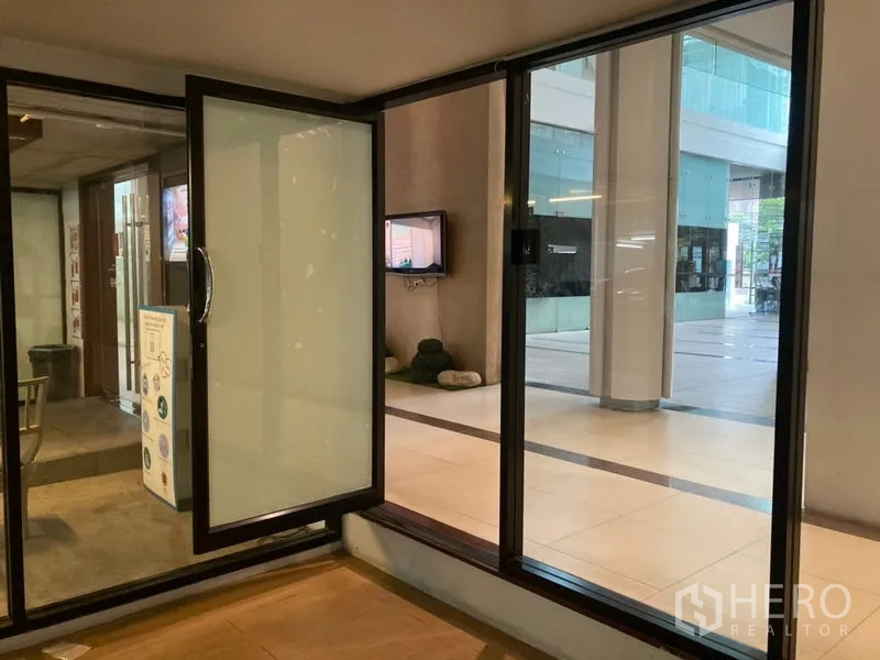 Retail Space for rent in Khlong Toei, Bangkok - Close-up of a hinged glass door leading to the shared atrium and tiled walkway.