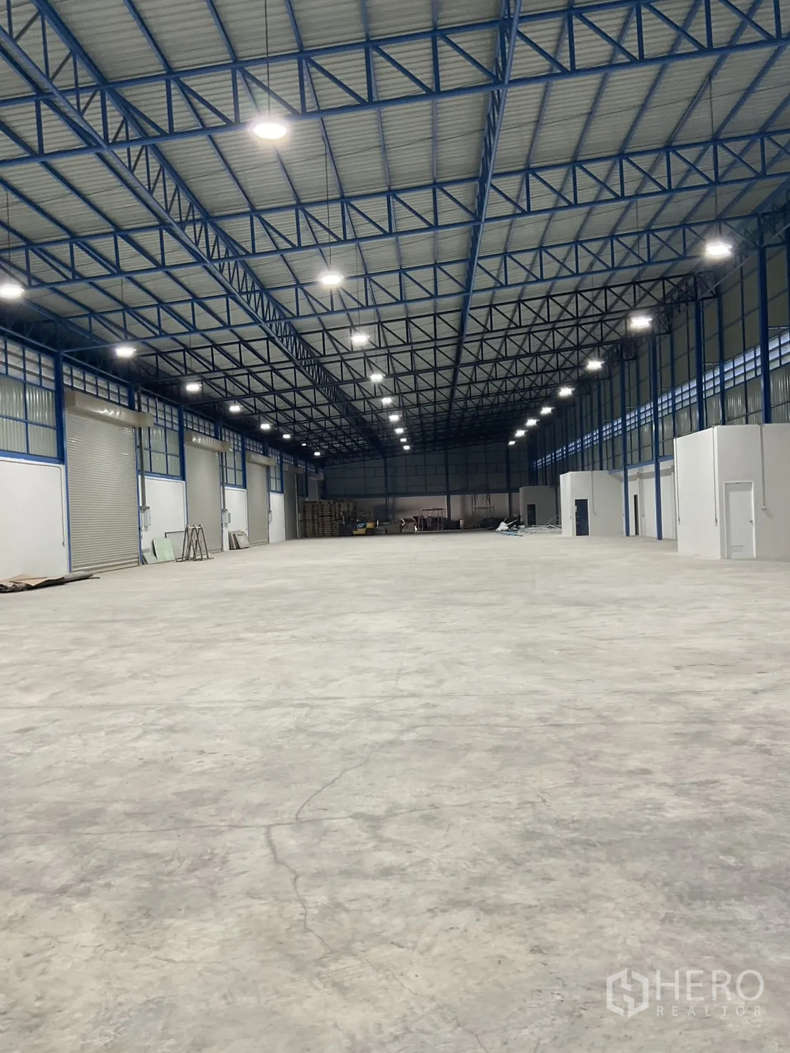 Warehouse for rent in Bang Bua Thong, Nonthaburi - Open-span interior with smooth concrete floor, ample lighting, and small side office rooms.
