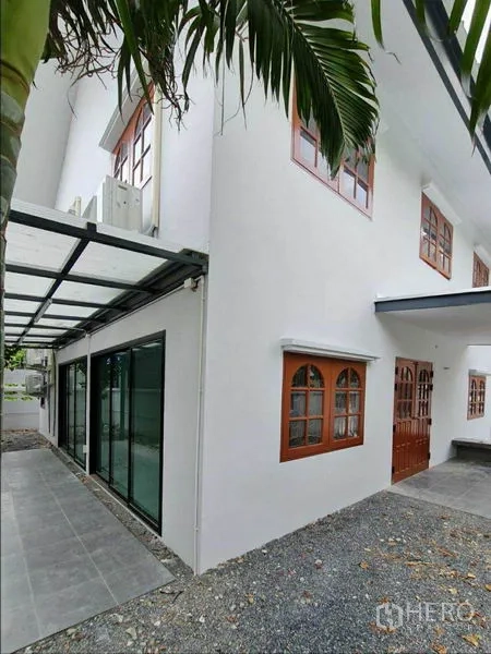 Home Office for rent in Lat Phrao, Bangkok - Side facade showing sliding glass doors, a covered walkway, and wooden-framed windows.