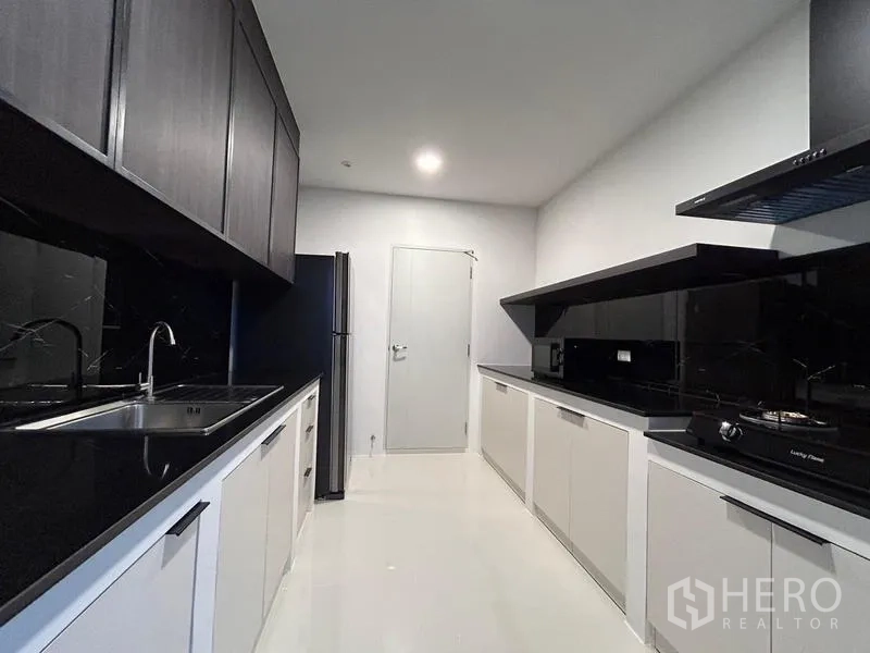 Detached House for rent or sale in Bang Phli, Samut Prakan - Galley Thai kitchen with black stone countertops, gas hobs and ample cabinetry.