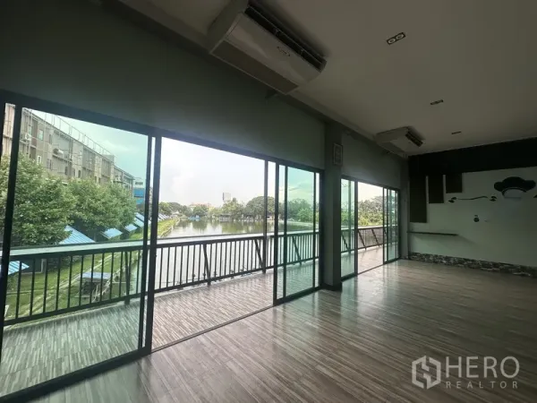 Standalone for rent in Prawet, Bangkok - Sliding glass doors to a long balcony overlooking a lakeside fish pond.
