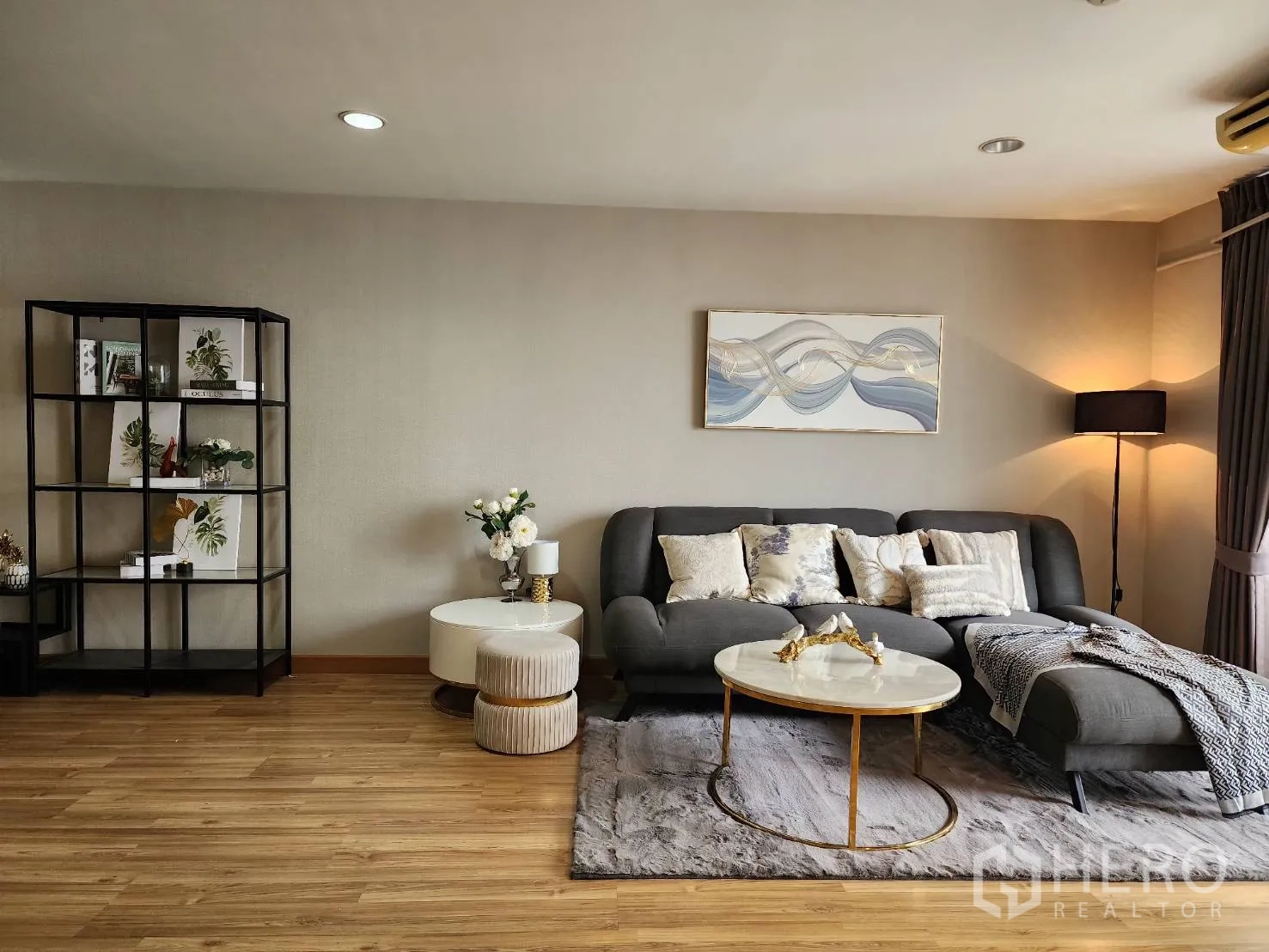 Condominium for rent in Watthana, Bangkok - Living room with shelving unit, rug, side tables and wood flooring.