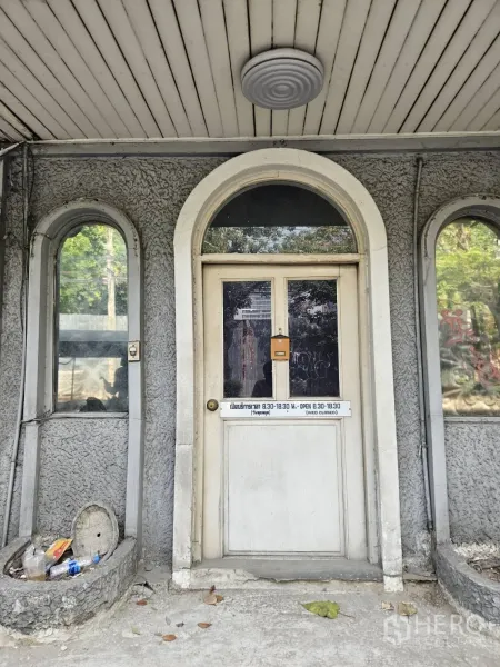 Shophouse for rent in Watthana, Bangkok - Front entrance of the shophouse featuring vintage door and arched side windows under a covered soffit.