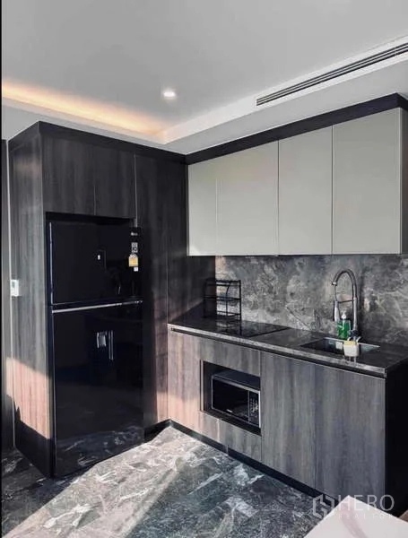 Condominium for rent in Khlong Toei, Bangkok - Sleek kitchenette with black fridge, stone countertop and sink.