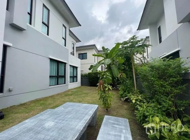Detached House for rent - Private lawn garden with tropical plants and outdoor bench between neighboring homes.