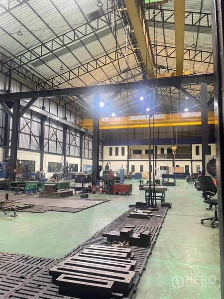 Factory for sale in Si Racha, Chon Buri - Night-lit factory interior with heavy-duty steel columns, cranes and workstations.
