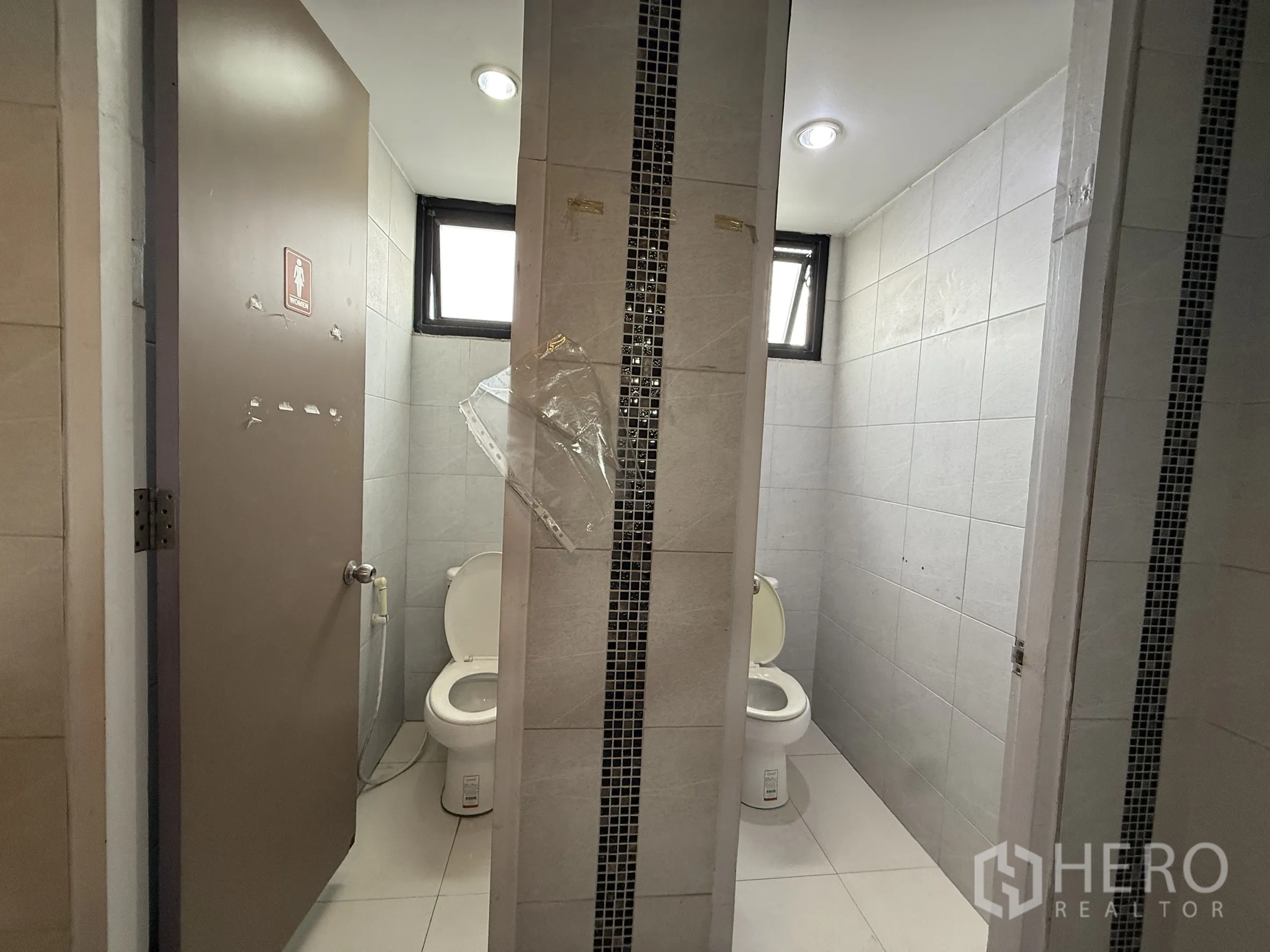 Office Space for rent in Din Daeng, Bangkok - Toilet stalls with small windows and tiled partitions in the shared bathroom.