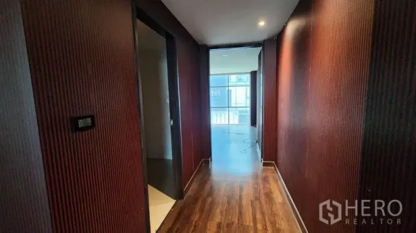 Shophouse for rent in Khlong Toei, Bangkok - Wood-floored corridor with textured walls leading toward front windows of the shophouse.