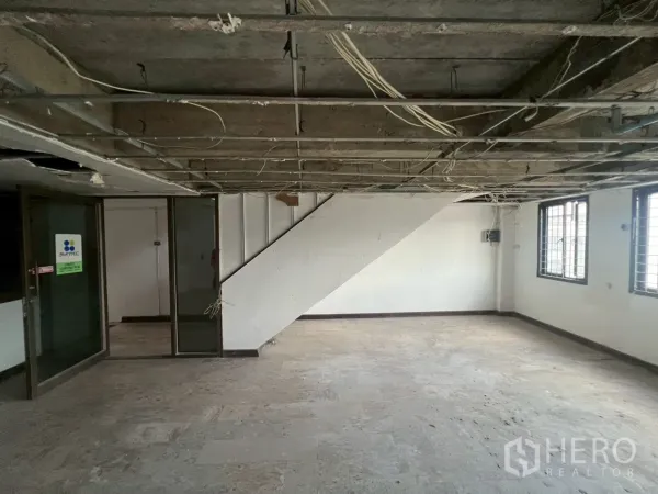 Shophouse for rent in Phra Khanong, Bangkok - Spacious room with internal staircase, side windows and glass partitions.