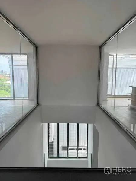 Home Office for rent or sale - Upper bridge corridor overlooking a double-height atrium with glass partitions on both sides.