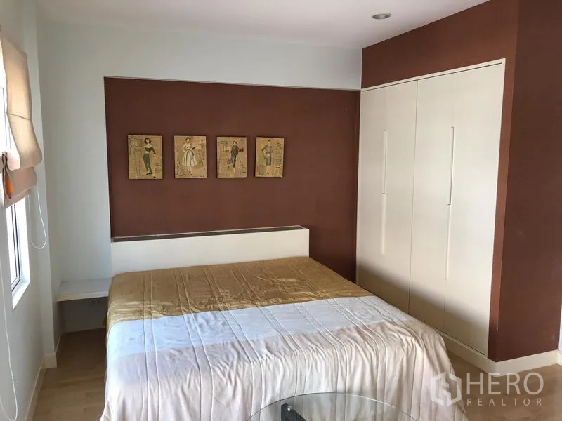 Townhouse for rent in Prawet, Bangkok - Master bedroom with feature wall, built-in wardrobe and bright windows.