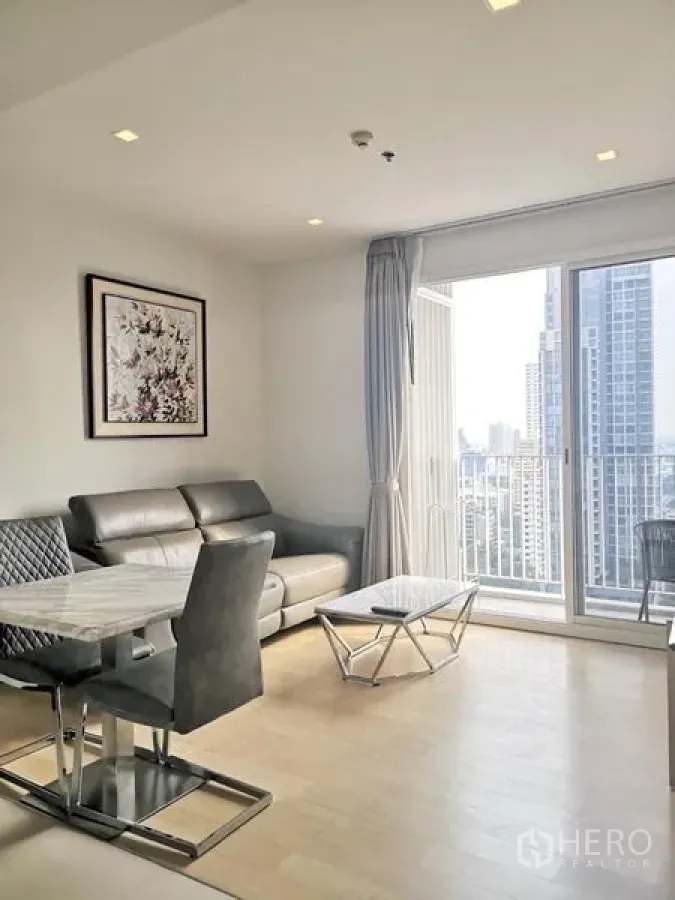 Condominium for rent in Watthana, Bangkok - Bright living room with leather sofa, marble coffee table and balcony offering a Bangkok skyline view.