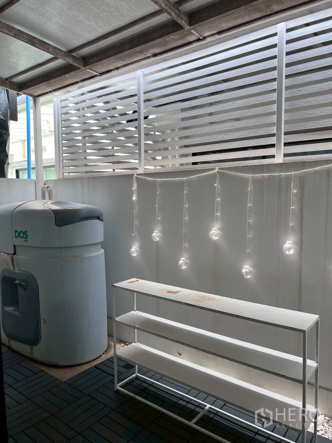 Townhouse for rent in Bang Phli, Samut Prakan - Rear utility zone with water tank, shelves, and decorative string lights.