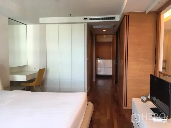 Condominium for rent in Pathum Wan, Bangkok - Bedroom with wood floors, built-in wardrobes, dressing desk and TV cabinet.