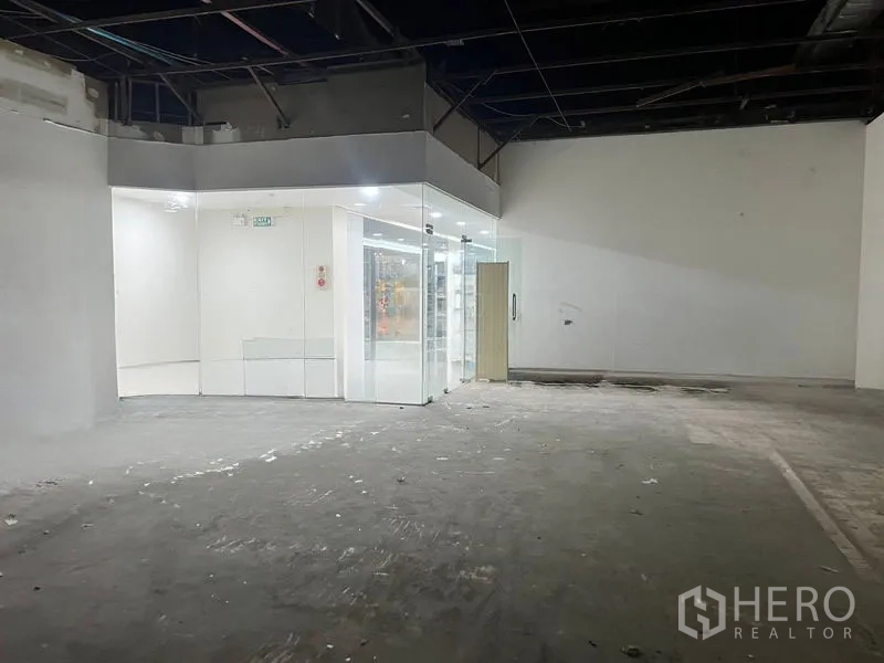 Retail Space for rent in Khlong Toei, Bangkok - Corner of the space with a glass room, exit signage, and high open ceiling.