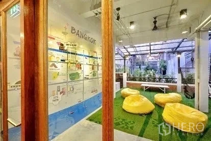 Shophouse for rent in Pathum Wan, Bangkok - Glass-walled lounge opening to a covered terrace with beanbags on turf.