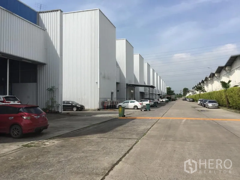 Factory for rent in Khlong Luang, Pathum Thani - Row of modern factory units with parking bays and a wide truck-friendly access road in Khlong Luang industrial area.