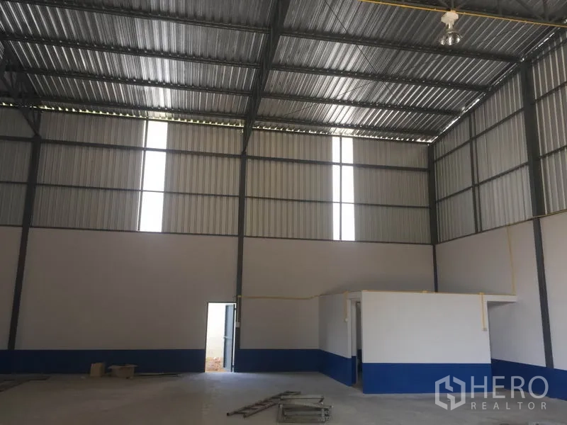 Warehouse for rent in Sai Mai, Bangkok - Rear section of the warehouse showing high roof, small utility room and side personnel door.