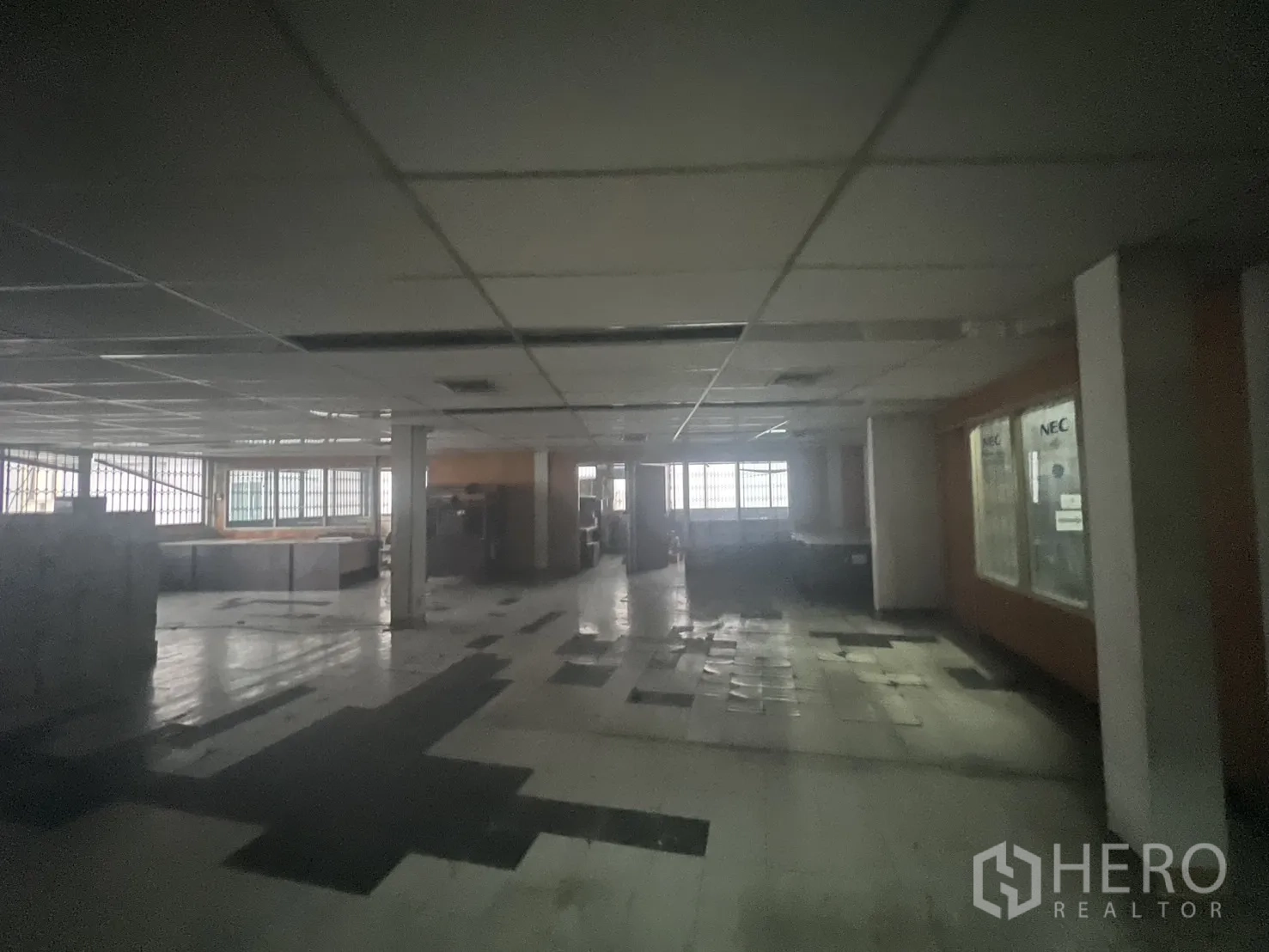 Shophouse for rent - Large vacant floor with drop ceiling, barred windows and worn tile flooring.