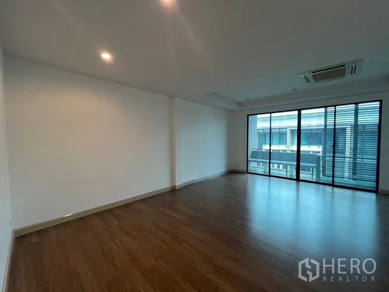 Townhouse for rent or sale in Khlong Toei, Bangkok - Spacious master bedroom with wide sliding doors leading to a balcony.