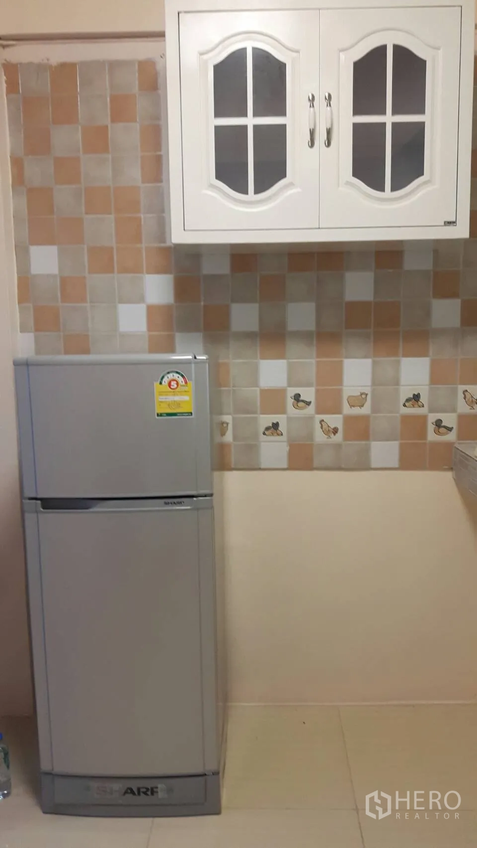Townhouse for rent in Khlong Toei, Bangkok - Close-up of the kitchen’s tiled backsplash, white wall cabinet, and silver refrigerator.