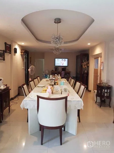 Detached House for sale in Suan Luang, Bangkok - Long dining room with large table for many guests under a tray ceiling chandelier.