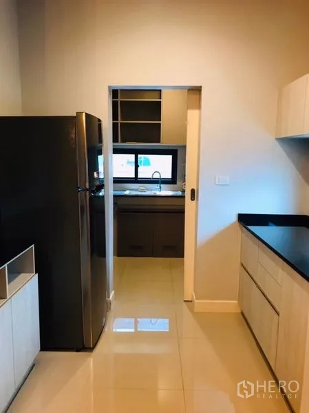 Detached House for rent or sale in Pathum Thani - Pantry and secondary kitchen with black countertops and a sliding door.