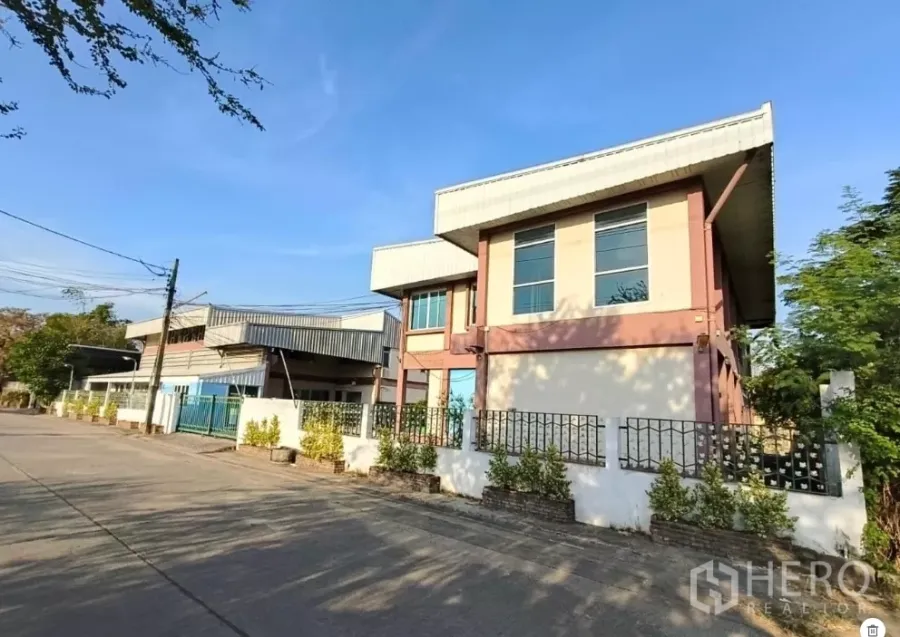 Warehouse for rent or sale in Min Buri, Bangkok - Street-facing two-storey warehouse with modern office frontage, gated fence and wide driveway in Min Buri.