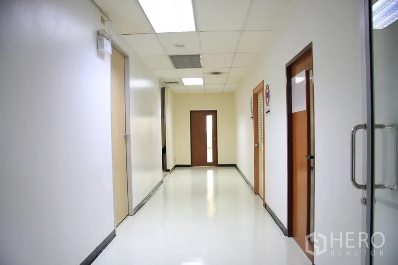 Office Space for rent in Chatuchak, Bangkok - Clean office corridor with white walls, ceiling lights and wooden doors.