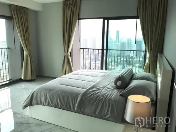 Condominium for rent in Khlong Toei, Bangkok - Bright master bedroom with floor-to-ceiling windows and Bangkok skyline view in a Khlong Toei condo.