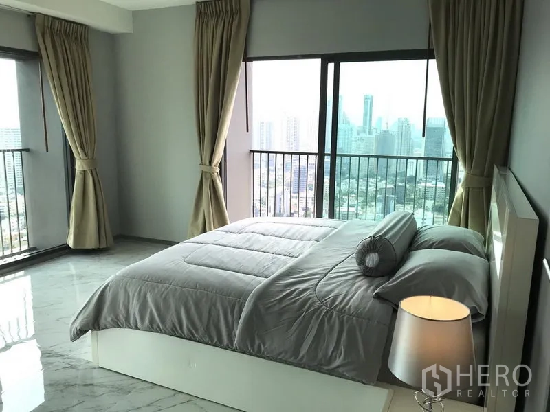 Condominium for rent in Khlong Toei, Bangkok - Bright master bedroom with floor-to-ceiling windows and Bangkok skyline view in a Khlong Toei condo.