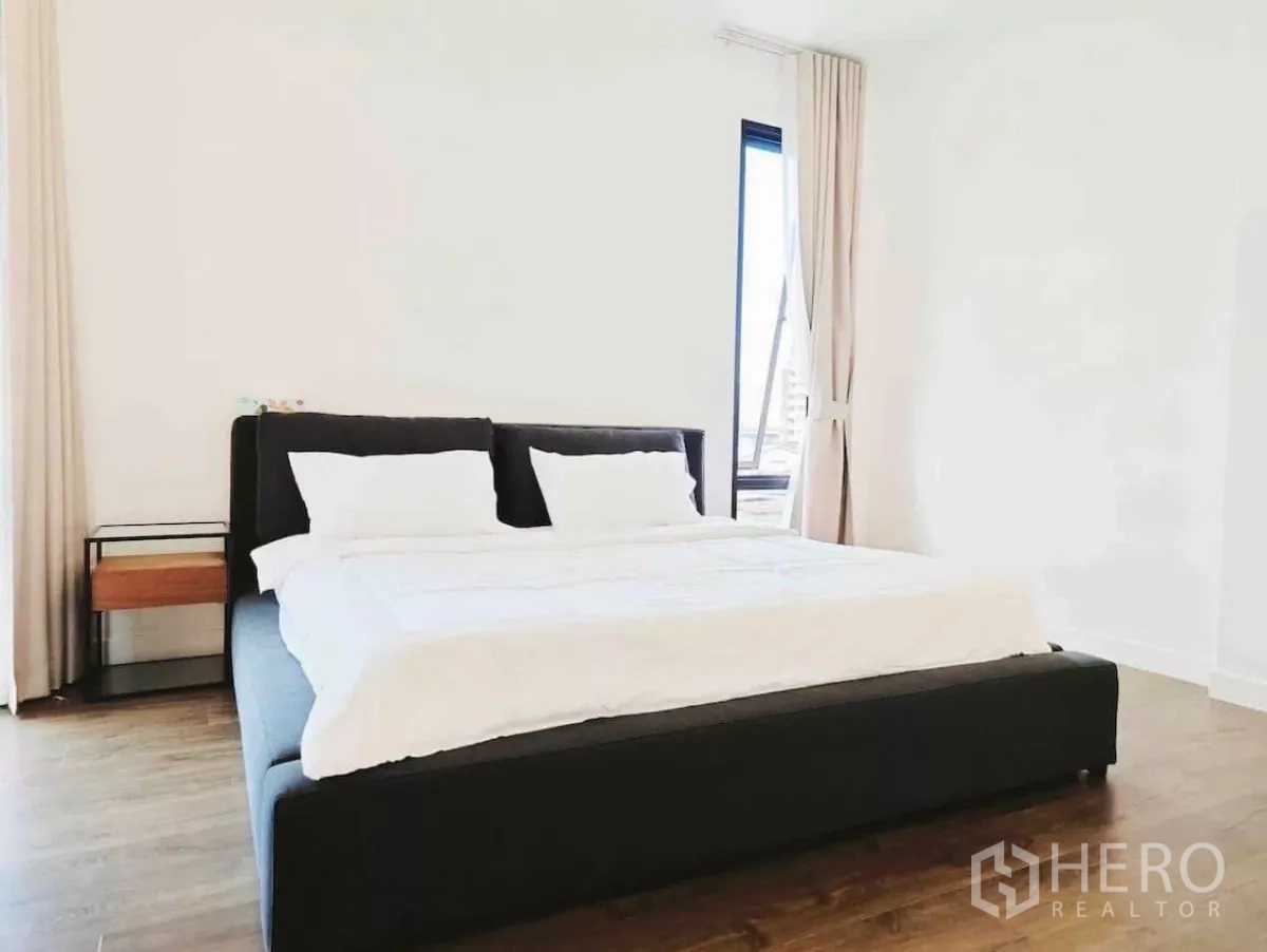 Detached House for rent in Phaya Thai, Bangkok - Bright bedroom with black upholstered bed, white walls and wood floor.