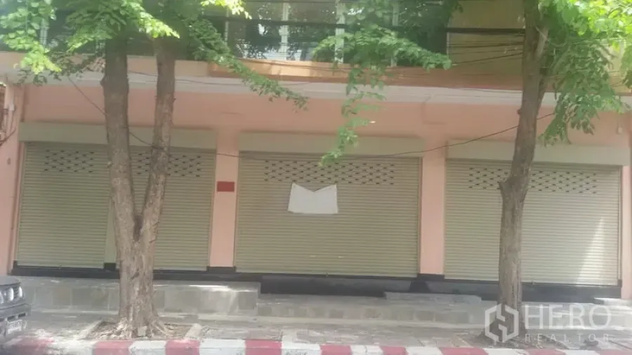 办公空间 出租在Sathon, Bangkok - 沙吞街边建筑外立面，三扇米色卷闸门与行道树成荫。