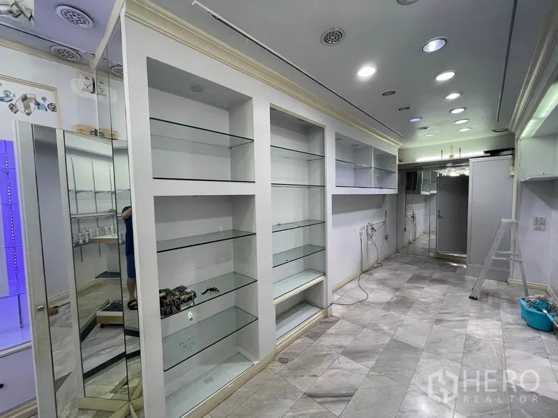 Shophouse for rent in Bang Rak, Bangkok - Built-in white cabinetry with multiple glass display shelves along the wall.