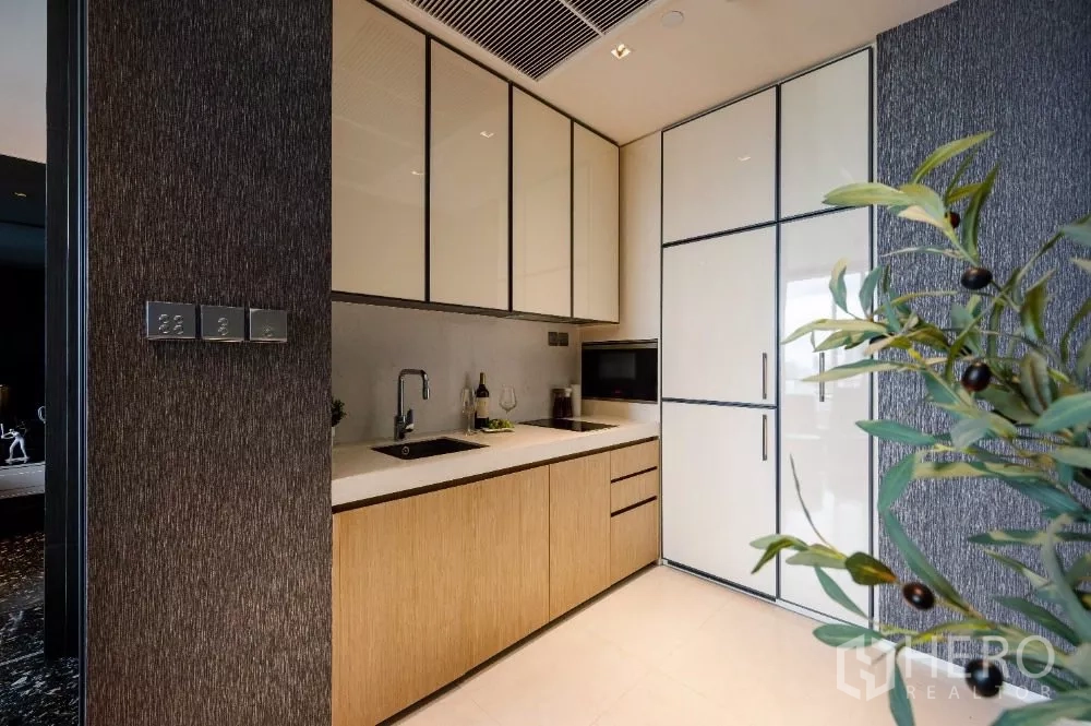 Condominium for rent or sale in Khlong Toei, Bangkok - Compact modern kitchenette with built-in cabinets, sink and tall fridge.