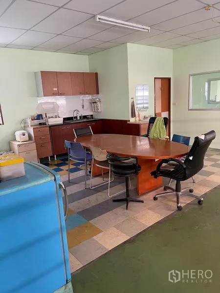 Warehouse for rent in Khan Na Yao, Bangkok - Staff pantry with cabinets and a meeting table adjacent to the warehouse operations area.