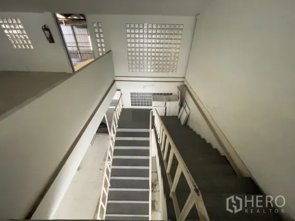 Warehouse for rent in Prawet, Bangkok - Interior staircase with glass-block wall leading to mezzanine offices.