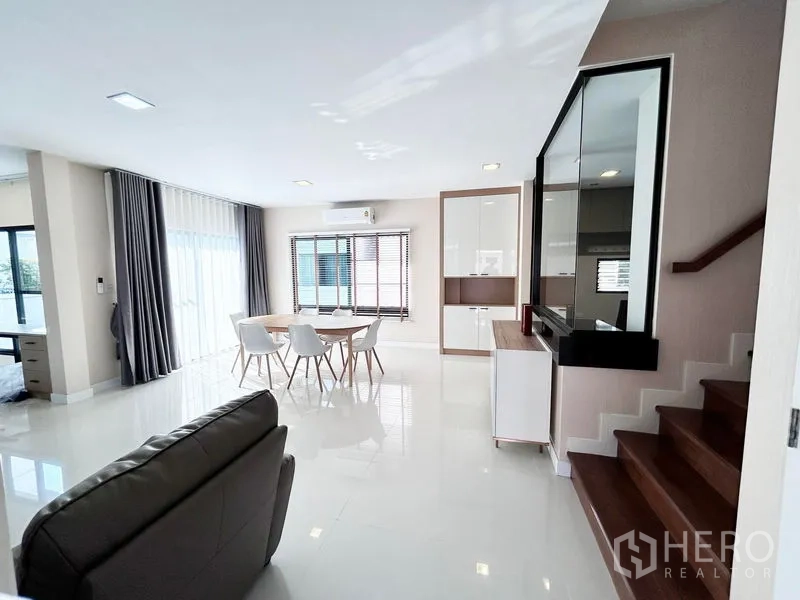 Detached House for rent or sale in Prawet, Bangkok - Open living space with dining set, stairway, and big windows.