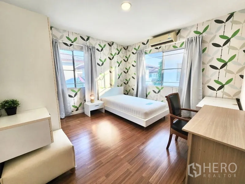 Detached House for rent in Prawet, Bangkok - Bright secondary bedroom with leaf-pattern wallpaper, desk and single bed.