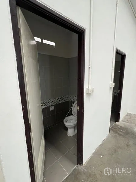 Warehouse for rent in Phra Samut Chedi, Samut Prakan - Warehouse restroom entrances with tiled floors and white framed doors.