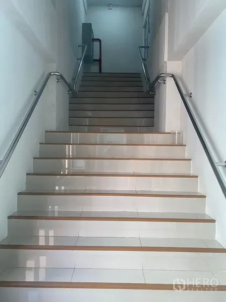 Office Space for rent in Bang Na, Bangkok - Wide interior staircase with stainless steel handrails and tiled steps in a commercial building.