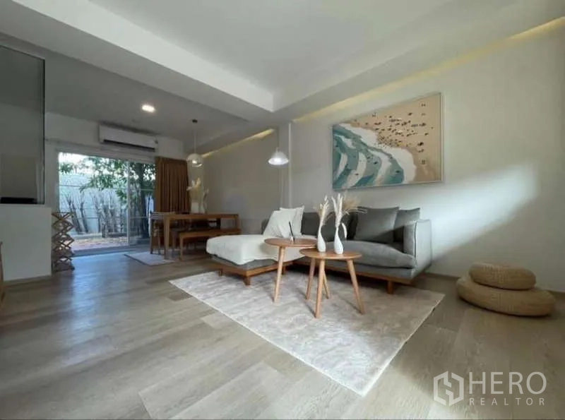 Townhouse for rent in Prawet, Bangkok - Open-plan living and dining with sectional sofa and sliders to patio