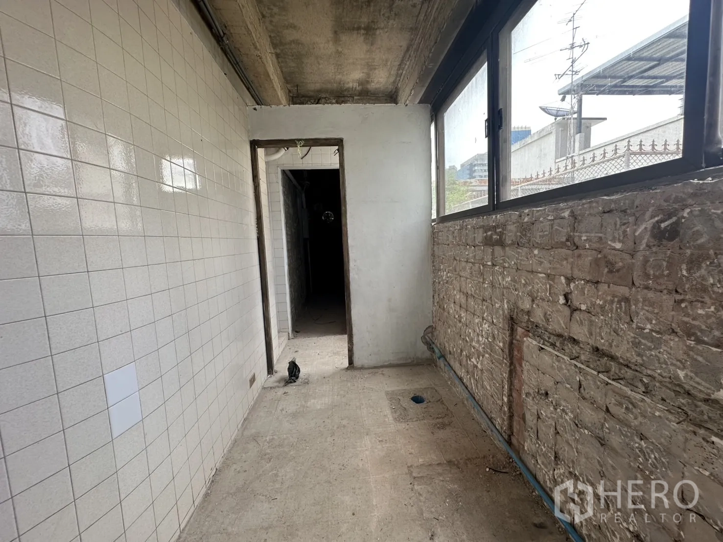 Retail Space for rent in Bang Rak, Bangkok - Long corridor with white tiled wall, drainage point and plumbing lines.