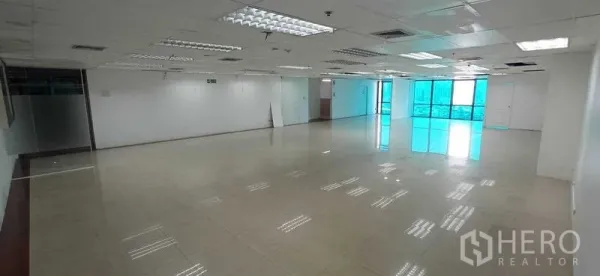 Office Space for rent in Huai Khwang, Bangkok - Long open office area leading to floor-to-ceiling windows and a small glass meeting room.