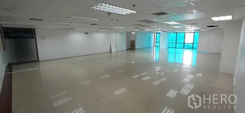 Office Space for rent in Huai Khwang, Bangkok - Long open office area leading to floor-to-ceiling windows and a small glass meeting room.