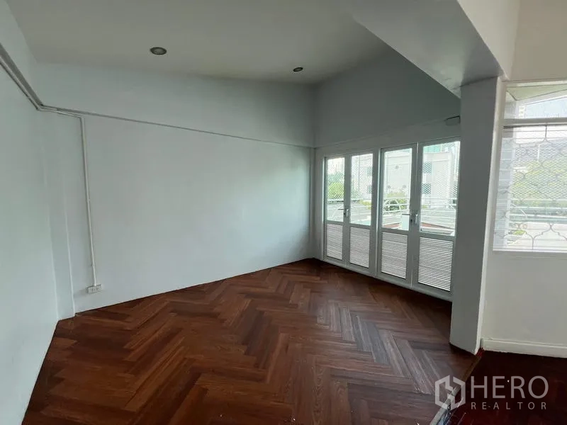 Home Office for rent in Watthana, Bangkok - Upper-floor room with herringbone wood floor and French doors opening to a balcony.