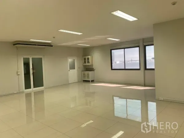 Office Space for rent in Bang Na, Bangkok - Bright open-plan office with glossy tile floors, large windows, pantry cabinet and glass doors.