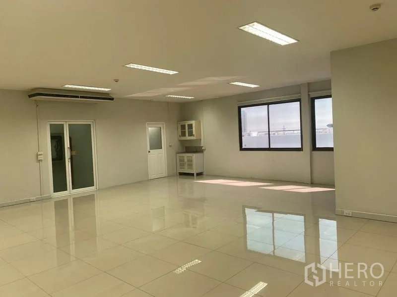Office Space for rent in Bang Na, Bangkok - Bright open-plan office with glossy tile floors, large windows, pantry cabinet and glass doors.